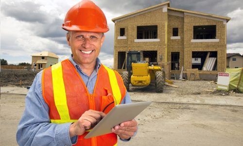 A royalty free image from the construction industry of a building contractor using a tablet computer at a new housing development.